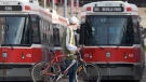 A cyclist walks past TTC streetcars in Toronto, Saturday, April 26, 2008. (Adrian Wyld / THE CANADIAN PRESS)      