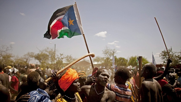 Members of the Taposa tribe, one waving the Sudan People's Liberation Movement's flag, celebrate the opening of a US-sponsored electrical power plant in the town of Kapoeta, southern Sudan on Friday, Feb. 4, 2011. (AP Photo/Pete Muller)