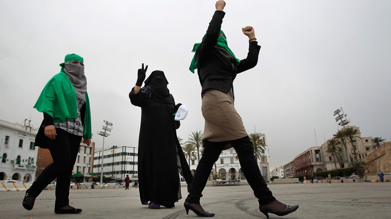 Following the announcement on Libyan state television that Moammar Gadhafi's forces have taken control of the Eastern city of Ajdabiya, Three Gadhafi supporters celebrate on Green Square in Tripoli, Libya, Tuesday March 15, 2011. (AP / Jerome Delay)
