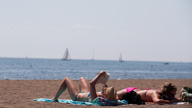 People read as they sunbathe on a warm summer day at Cherry Beach in Toronto on Thursday, Aug. 23, 2012. (The Canadian Press/Michelle Siu)