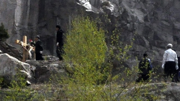 In this Monday, May 2, 2011 photo released by Gyeongbuk Provincial Police Agency Wednesday, May 4, 2011, police officers stand near the body of a man found crucified in Mungyong, south of Seoul, South Korea. (AP Photo/Gyeongbuk Provincial Police Agency)