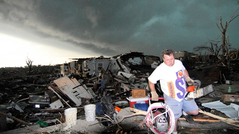 Mark Siler carries some salvageable items from the house of his friend Clay Warden as another storm approaches Joplin, Mo. on Monday, May 23, 2011. (AP / Mike Gullett)