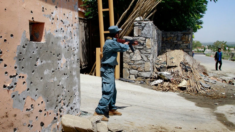 An Afghan policeman points his gun towards a pedestrian at the scene of a suicide attack outside the office of Parwan provincial governor in Chaharikar, Parwan province, north of Kabul, Afghanistan Tuesday, June 21, 2011. (AP / Musadeq Sadeq)