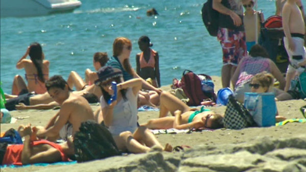 People sit in the sun at a beach in Toronto on Saturday, July 16, 2011.