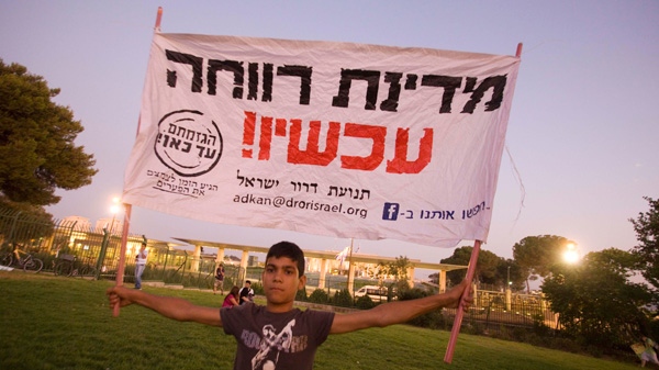 An Israeli youth carries a banner reading : 'Welfare state now!' as he and others demonstrate outside the Knesset, Israel's parliament, in Jerusalem, Tuesday, Aug. 2, 2011. (AP / Dan Balilty)