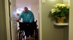 In this Dec. 21, 2013 photo, George Warren pulls his wheelchair through his apartment's front door at Village Crossroads, an affordable senior community in Nottingham, Md. Warren's wheelchair is too wide for the doorway and he can't afford a narrower model, so he folds it before carefully pulling it through. (AP / Patrick Semansky)