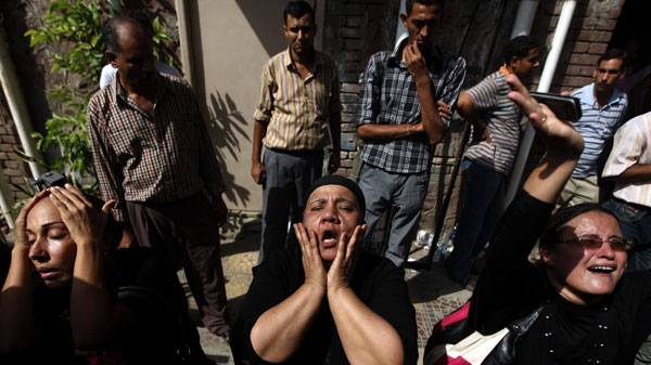 In this Monday, Oct. 10, 2011 file photo, Egyptian relatives of 17 of the Copts killed during clashes with the Egyptian army late Sunday, react after seeing their bodies outside the morgue of the Copts hospital in Cairo, Egypt. An army crackdown on a protest that killed more than 20 Christians has not only stunned Egyptians, it has left them with deeply torn feelings towards the force seen as the protector of the nation. Even supporters of the ruling military are grappling with the question of how the bloodshed could have happened. (AP Photo/Khalil Hamra, File)