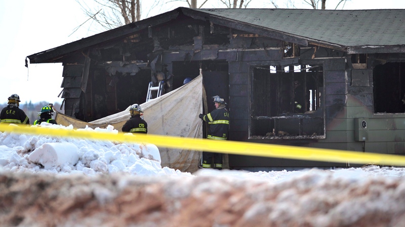 Charlottetown firefighters hold a tarp as officials remove bodies from an early morning fire in Charlottetown, P.E.I., Saturday, March 29, 2014. (THE CANADIAN PRESS/Nathan Rochford)