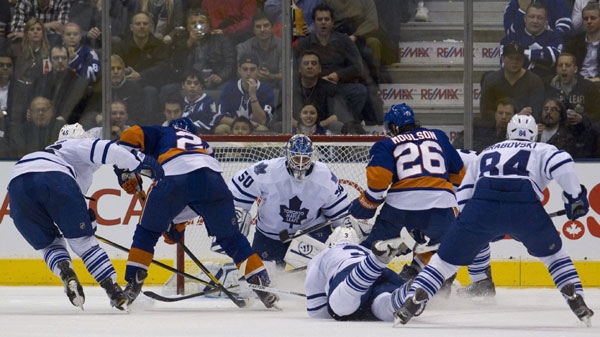 Toronto Maple Leafs' goaltender Jonas Gustavsson (center) tries to keep an eye on the puck as teammate Dion Phaneuf falls in front of the net and New York Islanders' Matt Moulson (right) and Kyle Okposo (left) drive towards the net during second period NHL hockey action against the New York Islanders in Toronto on Monday, January 23, 2012. THE CANADIAN PRESS/Pawel Dwulit