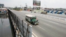 Passenger 'jeepneys,' modified jeeps, drive past walls covered with tarpaulin posters of the ongoing 45th Annual Board of Governors meeting of the Asian Development Bank at suburban Pasay city south of Manila, Philippines, Thursday May 3, 2012. (AP / Bullit Marquez)