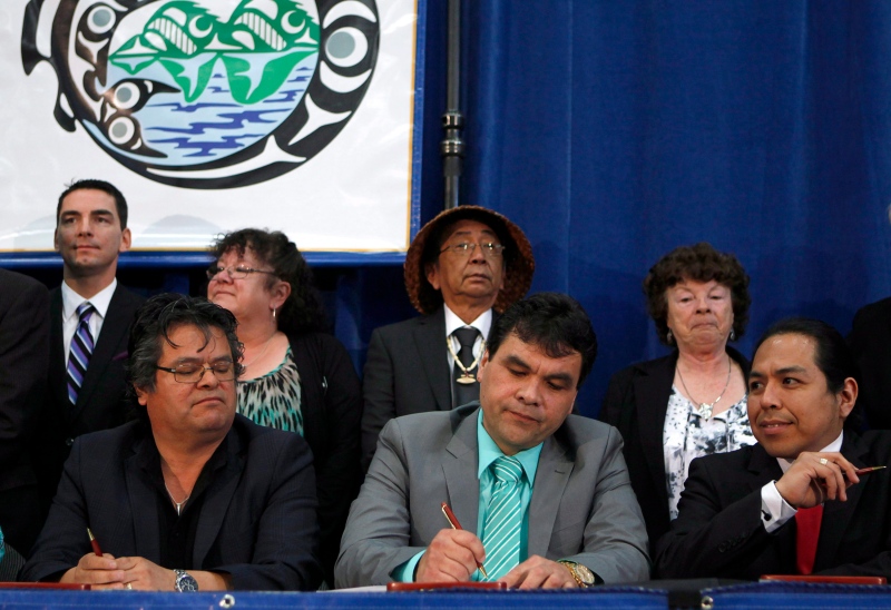 Beecher Bay First Nation Chief Russ Chipps signs an agreement-in-principle towards final treaties on Vancouver Island for approximately 1,565 hectares of crown land during an announcement at the Songhees Wellness Centre in Victoria, B.C., Thursday April 9, 2015. (THE CANADIAN PRESS/Chad Hipolito)