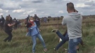 In this still from a video posted on social media, a Hungarian TV operator is shown after apparently tripping a man holding a girl.