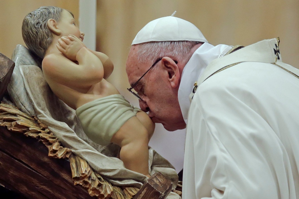 Pope Francis kisses a statue of Baby Jesus