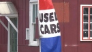 A used car flag flaps in the wind outside 'Quality Motors' on Cyrville Road in Ottawa. 