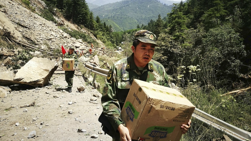 Chinese paramilitary policemen carry boxes of supplies past a section of road blocked by a landslide after an earthquake in Jiuzhaigou county in southwestern China's Sichuan province on Wednesday, Aug. 9, 2017. (Chinatopix)