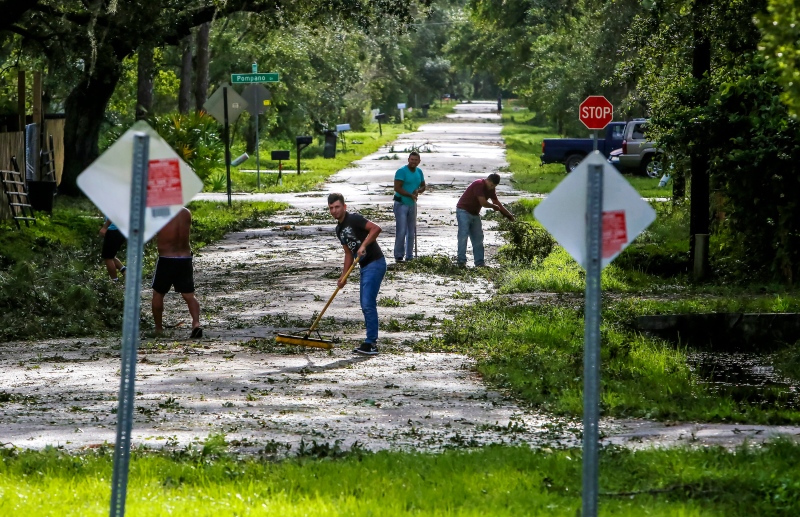 Neighbors help each other clear their road of debris in Kissimmee, Fla., Monday, Sept. 11, 2017, as residents begin to clean up after Hurricane Irma plowed through the state. (Jacob Langston/Orlando Sentinel via AP)