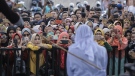 People use their mobile phones to take pictures as a Shariah law official whips a woman who is convicted of prostitution during a public caning outside a mosque in Banda Aceh, Indonesia, Friday, April 20, 2018. (AP Photo/Heri Juanda)