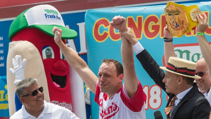Reigning champion Joey Chestnut, centre, celebrates with Master of ceremonies George Shea, right, and Brooklyn District Attorney Eric Gonzalez, after winning the men's competition of the Nathan's Famous Fourth of July hot dog eating contest in the final seconds of the competition, Wednesday, July 4, 2018, in New York's Coney Island. (AP / Mary Altaffer)