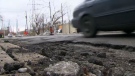 A car drives on a road covered in potholes. 