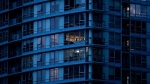 A resident, centre, in an upper floor condo is silhouetted as people have been urged to stay home to help prevent the spread of the coronavirus, in Vancouver, on Monday, March 23, 2020. THE CANADIAN PRESS/Darryl Dyck