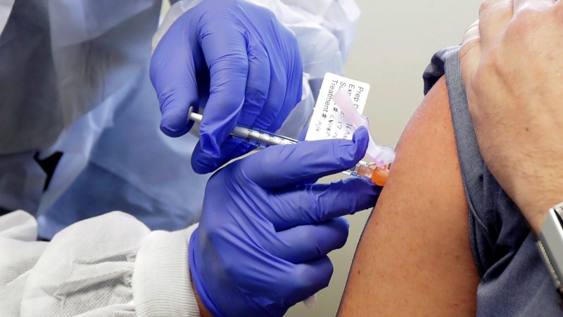 In this March 16, 2020 file photo, a patient receives a shot in the first-stage safety study clinical trial of a potential vaccine for COVID-19, the disease caused by the new coronavirus, at the Kaiser Permanente Washington Health Research Institute in Seattle. (AP Photo/Ted S. Warren, File)