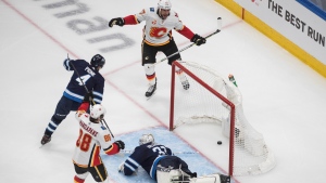 Calgary Flames' Andrew Mangiapane (88) and Milan Lucic (17) celebrate a goal on Winnipeg Jets goalie Connor Hellebuyck (37) as Jets' Neal Pionk (4) defends during third period NHL qualifying round game action in Edmonton, on Tuesday August 4, 2020. THE CANADIAN PRESS/Jason Franson