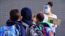 A teacher wearing protective equipment greets her students in the school yard at the Philippe-Labarre Elementary School in Montreal, on Aug. 27, 2020. THE CANADIAN PRESS/Paul Chiasson