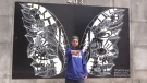 Wesley Shaw takes a selfie with the ‘Wings” mural by artist Kelsey Montague in St. Thomas, Ont. on April 6, 2021. (Brent Lale/CTV London)