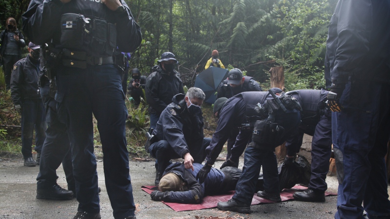 RCMP officers, including two wearing the 'Thin Blue Line' patch, arrest a man during an anti-logging protest in Caycuse, B.C. on Tuesday, May 18, 2021. THE CANADIAN PRESS/Jen Osborne 