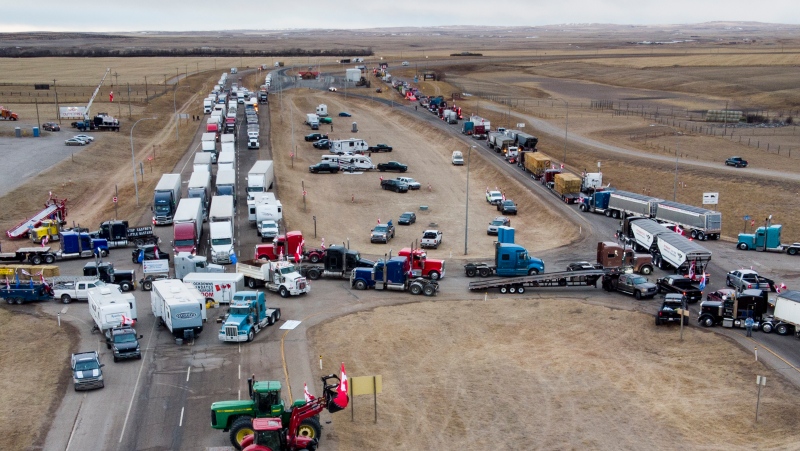 Demonstrators gather as a truck convoy blocks the highway the busy U.S. border crossing in Coutts, Alta., on Jan. 31, 2022. THE CANADIAN PRESS/Jeff McIntosh