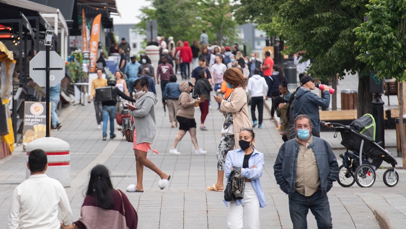 FILE - People walk by outdoor terraces in Old Montreal, Sunday, May 30, 2021, as the COVID-19 pandemic continues in Canada and around the world. THE CANADIAN PRESS/Graham Hughes