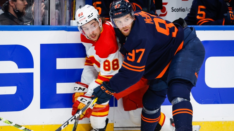 Calgary Flames forward Andrew Mangiapane, left, is checked by Edmonton Oilers centre Connor McDavid during first period NHL second round playoff hockey action in Edmonton, Sunday, May 22, 2022 (The Canadian Press/Jeff McIntosh).