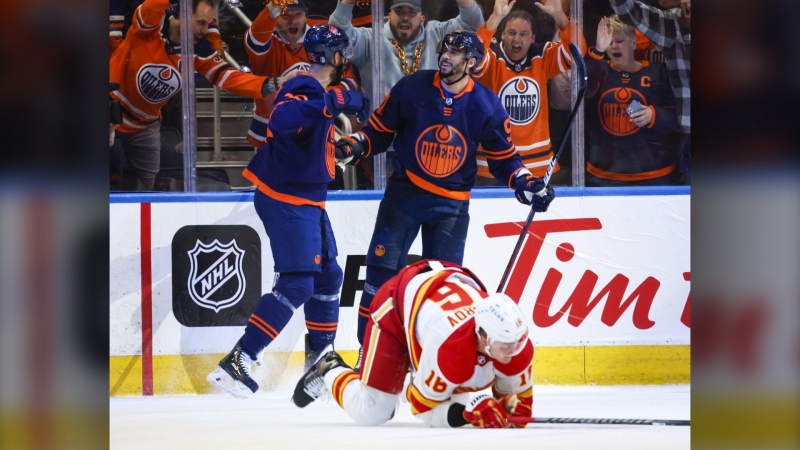 Calgary Flames defenceman Nikita Zadorov, right, picks himself up as Edmonton Oilers winger Evander Kane, centre, celebrates his goal with a teammate during first period NHL second-round playoff hockey action in Edmonton, Tuesday, May 24, 2022.(THE CANADIAN PRESS/Jeff McIntosh)