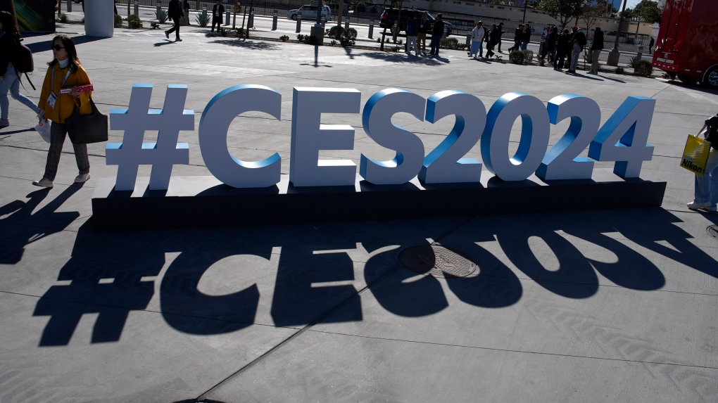 People walk by a CES sign during the CES tech show