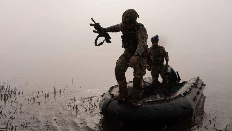 A Ukrainian serviceman jumps out of the boat onto the shore of Dnipro at the frontline near Kherson, Ukraine, Sunday, Oct. 15, 2023. (AP Photo/Alex Babenko) 