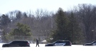 A police officer walks across a road after two police officers and a first responder were shot and killed Sunday, Feb. 18, 2024, in Burnsville, Minn. (AP Photo/Abbie Parr)