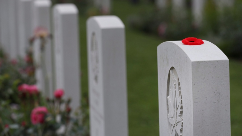An artificial red poppy is placed on the headstone of a Canadian World War II soldier prior to a ceremony at the Beny-sur-Mer Canadian War Cemetery in Reviers, Normandy, France, Wednesday, June 5, 2019. The cemetery contains 2,049 headstones marking the dead of the 3rd Division and graves of 15 airmen. (AP Photo/David Vincent)