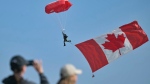 A large Canadian national flag hangs from a parachutist as he lands ahead of the Canadian commemorative ceremony marking the 80th anniversary of the World War II D-Day at the Juno Beach Centre near Courseulles-sur-Mer, Normandy, Thursday, June 6, 2024. (Lou Benoist, Pool via AP)