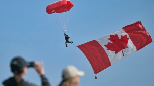 A large Canadian national flag hangs from a parachutist as he lands ahead of the Canadian commemorative ceremony marking the 80th anniversary of the World War II D-Day at the Juno Beach Centre near Courseulles-sur-Mer, Normandy, Thursday, June 6, 2024. (Lou Benoist, Pool via AP)