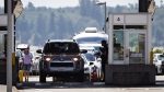 A Canada Border Services Agency officer speaks to a motorist entering Canada at the Douglas-Peace Arch border crossing, in Surrey, B.C., on Monday, August 9, 2021. (Darryl Dyck / The Canadian Press)