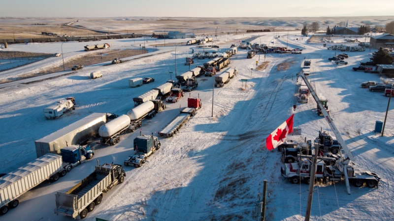 A truck convoy of anti-COVID-19 vaccine mandate demonstrators block the highway at the busy Canada-U.S. border crossing in Coutts, Alta., Wednesday, Feb. 2, 2022. (THE CANADIAN PRESS/Jeff McIntosh)