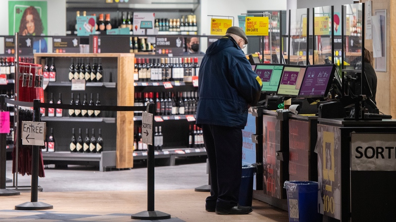 A man purchases alcohol at a SAQ outlet in Montreal, Tuesday, January 18, 2022. (Graham Hughes, The Canadian Press)