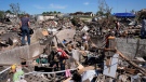 FILE - Family members clean belongings out of a tornado damaged home, Thursday, May 23, 2024, in Greenfield, Iowa. (Charlie Neibergall / The Associated Press)
