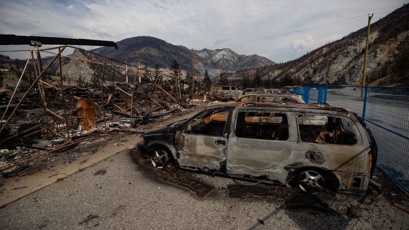 The remains of a large structure and vehicles destroyed by the Lytton Creek wildfire are seen on the side of the Trans-Canada Highway near Lytton, B.C., on August 15, 2021. (Darryl Dyck/The Canadian Press)