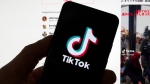 FILE - The TikTok logo is seen on a mobile phone in front of a computer screen which displays the TikTok home screen, Saturday, March 18, 2023, in Boston. (AP Photo/Michael Dwyer, File)