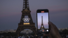 A person takes video of Olympic rings on the Eiffel Tower Friday, June 7, 2024, in Paris.  (AP Photo/Aurelien Morissard)