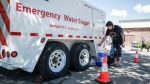 Liz Workun fills water jugs from an emergency supply provided by the city as work to repair a major water main stretches into a second day in Calgary, Friday, June 7, 2024.THE CANADIAN PRESS/Jeff McIntosh