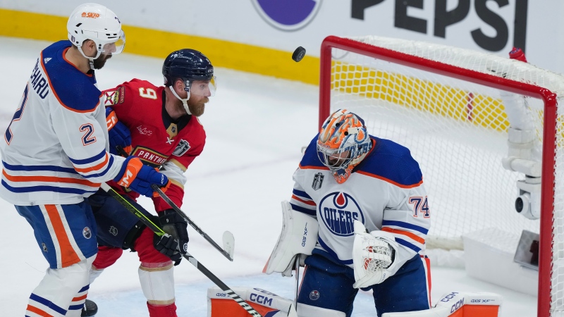 Edmonton Oilers goaltender Stuart Skinner (74) makes a save as Florida Panthers' Sam Bennett (9) eyes the loose puck next to Oilers' Evan Bouchard (2) during second period action in Game 1 of the NHL Stanley Cup final in Sunrise, Fla. on June 8, 2024. (Nathan Denette/The Canadian Press)