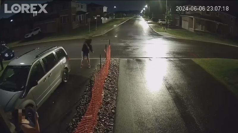 Home security camera footage shows a man in a hoodie standing on an adjacent driveway throwing eggs at a Barrhaven home shortly after 11 p.m. June 6, 2024. (Supplied)