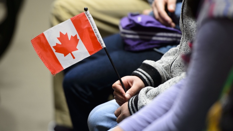 A young new Canadian holds a flag as she takes part in a citizenship ceremony on Parliament Hill in Ottawa on Wednesday, April 17, 2019. (THE CANADIAN PRESS/Sean Kilpatrick)
